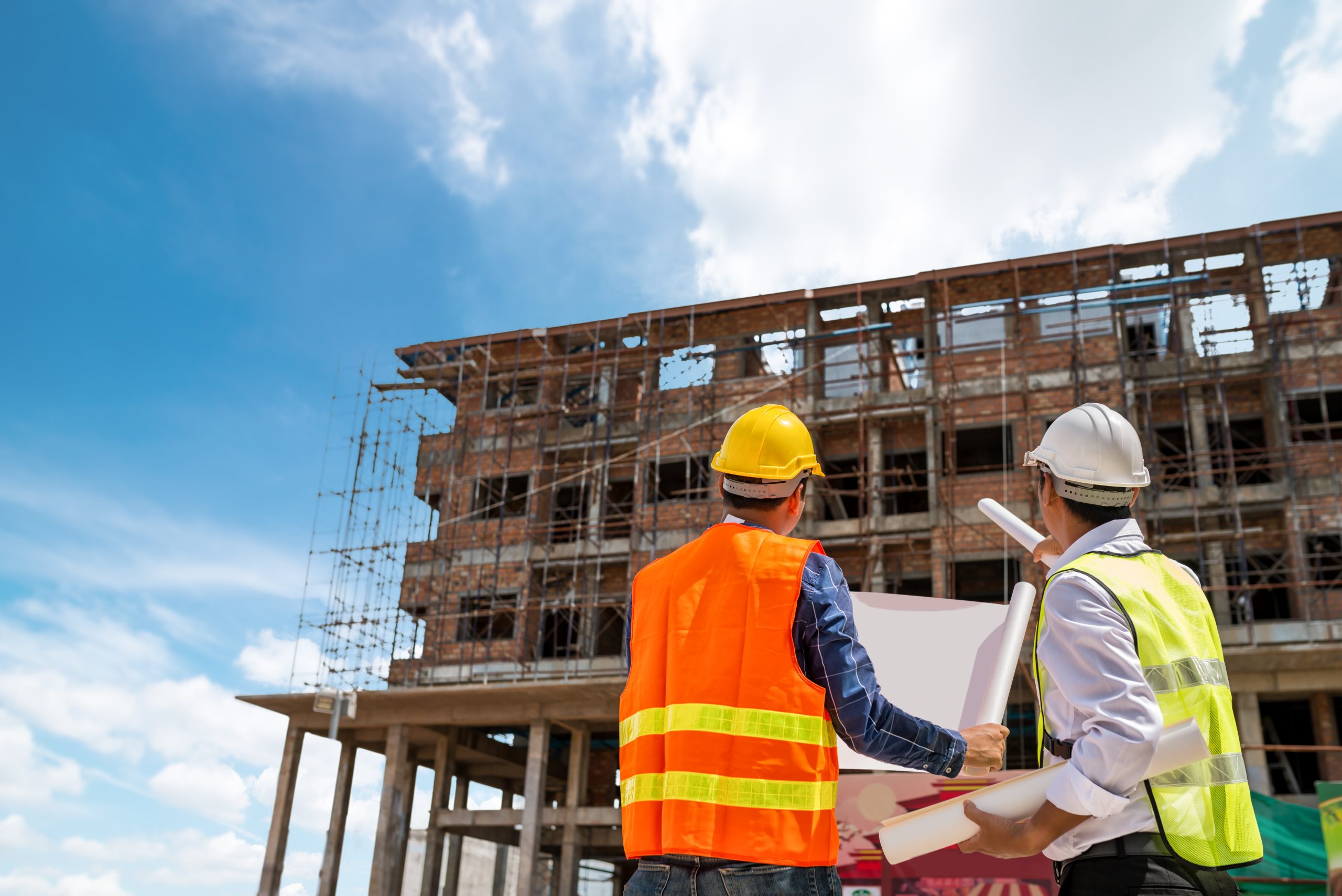 Businessman engineer looking blueprint in a building to  discussion with architects at construction site or building site of highrise building